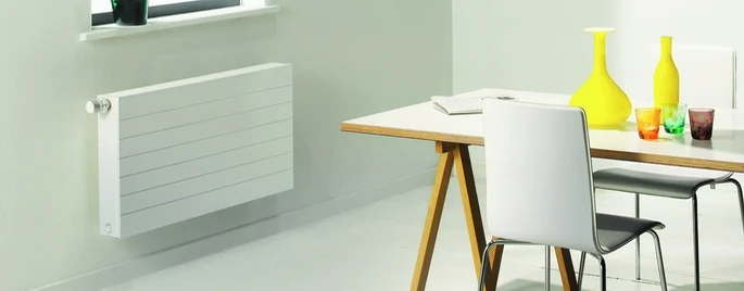 Radiador de panel junto a una mesa de comedor sin obstáculos delante — reparacioncalderas.madrid